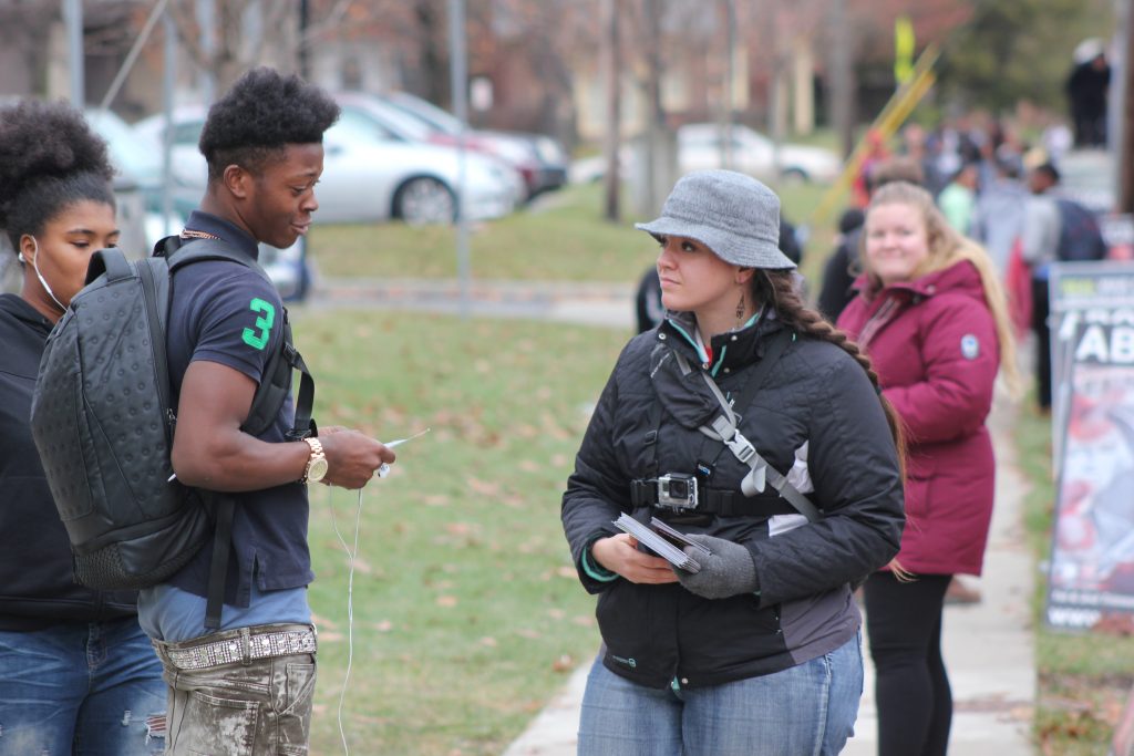 Rachel Burkey, during a high school outreach, shows two students the hidden victims of abortion.